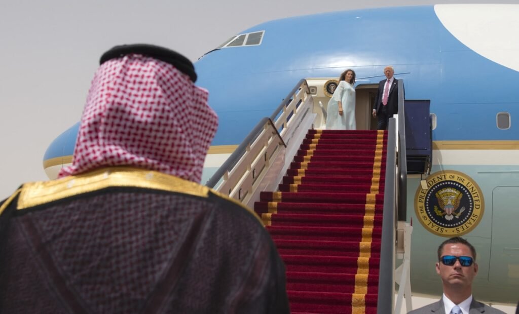 US President Donald Trump and Melania Trump atop the Air Force One stairs greeted by a Saudi official, highlighting the high-level diplomacy supporting a potential US-Saudi nuclear agreement.