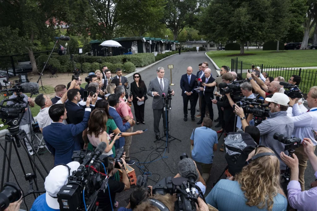 A photograph showing US Treasury Secretary Scott Bessent speaking to a dense crowd of reporters and television cameras outside the West Wing of the White House, visually representing the high-stakes economic and diplomatic messaging battles that underscore the escalating threats to US Global Leadership on multiple geopolitical fronts.