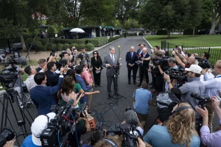 A photograph showing US Treasury Secretary Scott Bessent speaking to a dense crowd of reporters and television cameras outside the West Wing of the White House, visually representing the high-stakes economic and diplomatic messaging battles that underscore the escalating threats to US Global Leadership on multiple geopolitical fronts.
