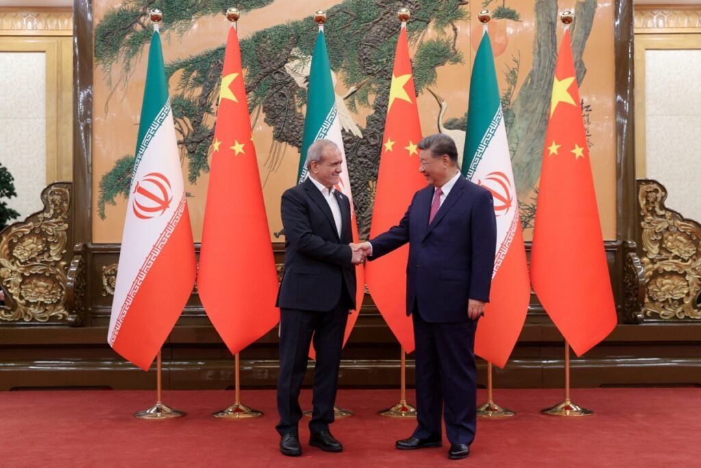 Iranian President Masoud Pezeshkian shakes hands with Chinese President Xi Jinping in Beijing, highlighting China's pivotal role in determining the outcome of US Sanctions on Iran.