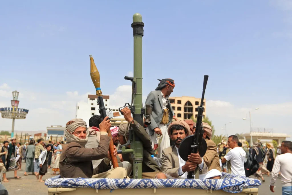 الدور الاستراتيجي لليمن في الأمن البحري بعد الحرب Armed Yemeni fighters holding RPGs and machine guns in the back of a pickup truck, illustrating Yemen's strategic role and challenges in ensuring regional Post-War Maritime Security.