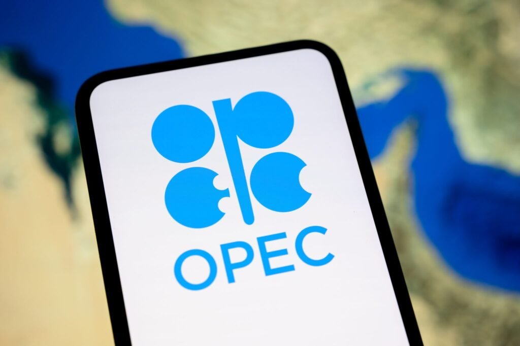 OPEC Future Faces Severe Structural Strain After Iran War A phone displays the OPEC logo over a Strait of Hormuz map as the OPEC Future faces severe structural strain after the Iran war.
