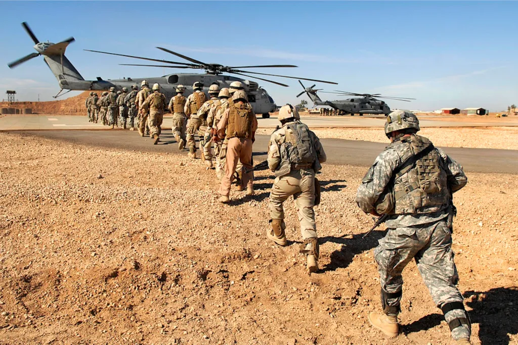 تراجع الهيمنة الأمريكية في الشرق الأوسط في ظل واقع متعدد الأقطاب US military personnel in desert camouflage walking toward transport helicopters on an airfield, illustrating the prolonged military footprints and strategic shifts surrounding US Middle East Hegemony.
