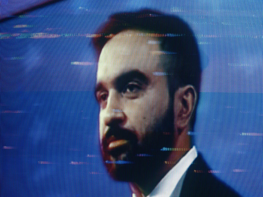 A close-up portrait of Zohran Mamdani displayed on a pixelated television screen, reflecting the media reaction to his controversial Netanyahu Stunt.