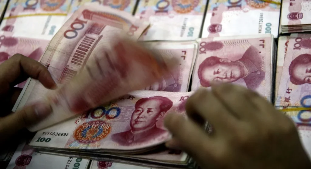 China’s Currency Push Counters Dollar Dominance in Gulf Hands count thick stacks of red 100-yuan banknotes, symbolizing the financial mechanisms driving China's Currency expansion across global markets.