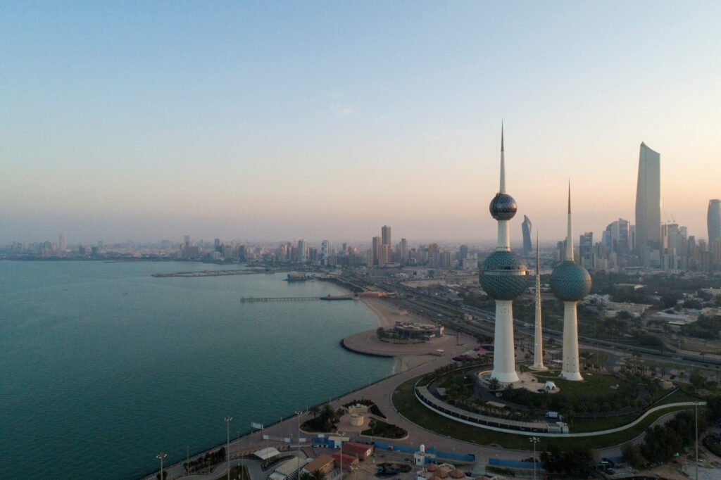 Kuwait water security: Iran exposes Gulf’s weak link Aerial view of Kuwait City at dawn featuring the iconic Kuwait Towers and its sprawling skyline along the Persian Gulf coastline, visually emphasizing the nation's heavy reliance on these territorial waters for desalination—a reality that exposes the underlying fragility of Kuwait water security, making it the critical geopolitical weak link that Iran's regional strategy threatens to exploit