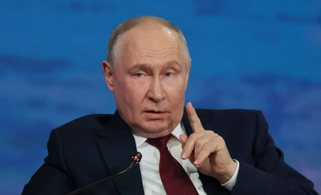 Russia-Iran military cooperation binds Ukraine and Mideast Russian President Vladimir Putin raising his right index finger while speaking into a microphone during a formal public address, visually representing his leadership role in advancing Russia-Iran military cooperation that directly binds the ongoing Ukraine conflict with evolving Middle Eastern security dynamics.