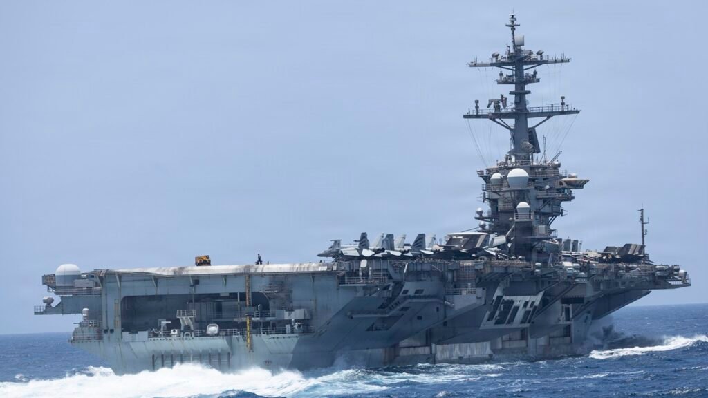 The aircraft carrier USS Abraham Lincoln sails through open ocean waters with fighter jets parked on deck, illustrating the operational strains of an extended USS Abraham Lincoln Deployment.