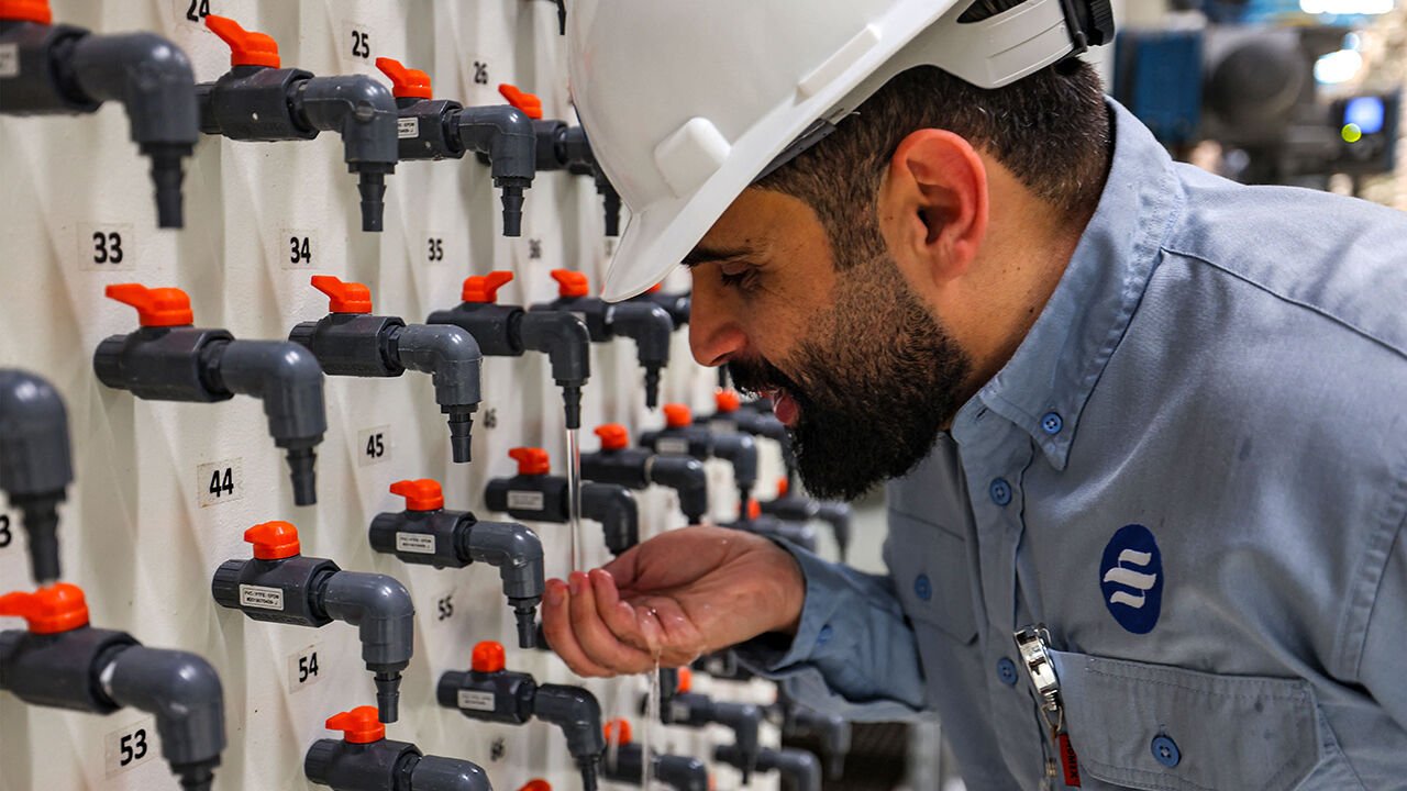 General manager, Mohamed Ali al-Qahtani, inspects desalinated drinking water from a tap at the facility in Ras al-Khair along the Gulf coast in eastern Saudi Arabia.