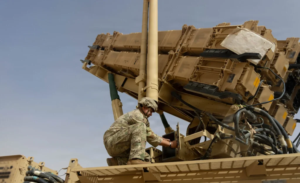 A US military service member inspects a Patriot missile air defense launcher system, illustrating the operational and logistical pressures driving the US Missile Shortage.