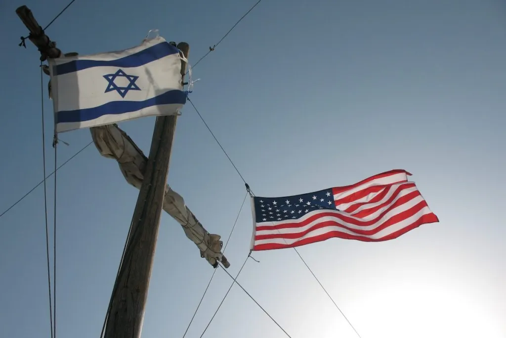 شرق أوسط ما بعد أمريكا: ماذا يعني ذلك لإسرائيل Flags of Israel and the United States waving against a clear sky, illustrating the evolving bilateral alliance and strategic implications for Israel in a Post-American Middle East.