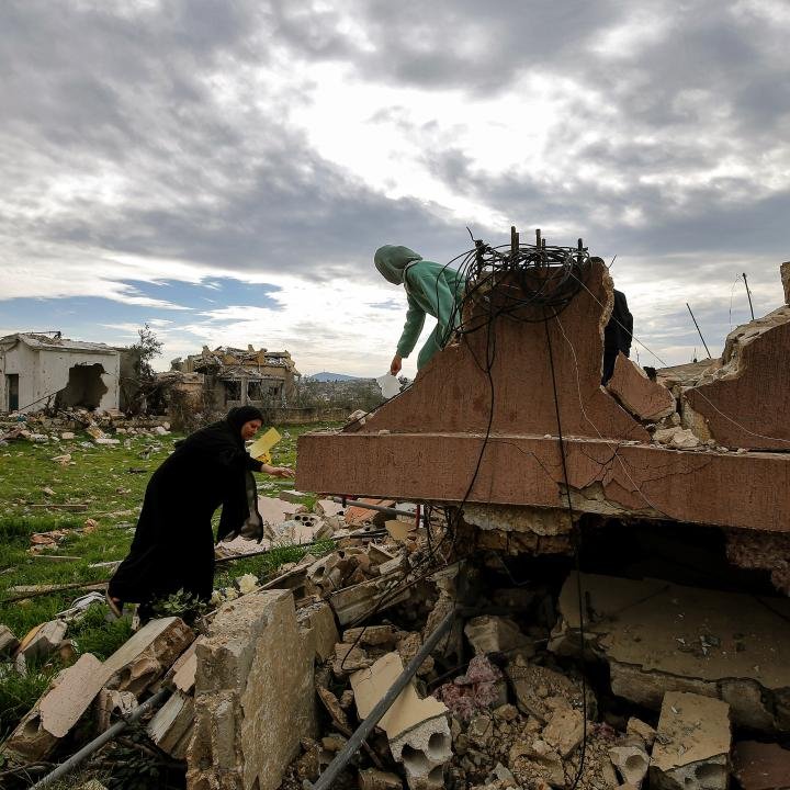 Israel Lebanon Peace Hinges on Hezbollah Disarmament Civilians inspect the concrete rubble of destroyed homes in a conflict-damaged area, illustrating the high stakes surrounding Israel Lebanon peace.