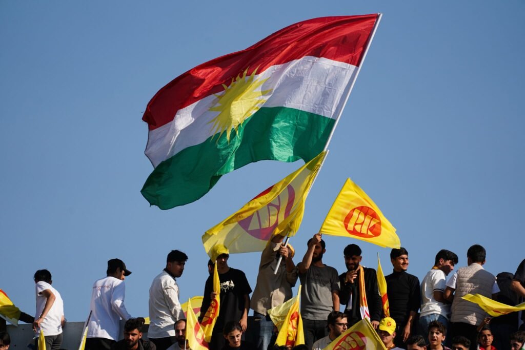 تغيرات الفيدرالية في إقليم كردستان تحت ضغط النخبة A crowd of supporters at Duhok International Stadium waves yellow Kurdistan Democratic Party flags alongside the large Kurdish national flag, reflecting political mobilization around Kurdistan Region Federalism.
