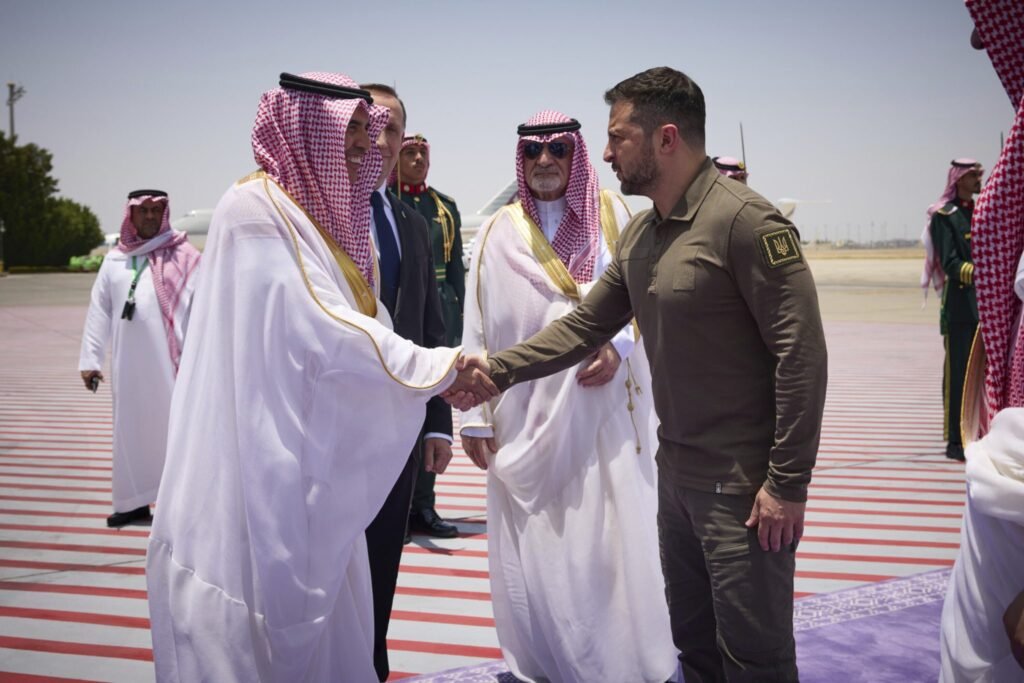 Ukrainian President Volodymyr Zelenskyy shaking hands with Saudi Arabian dignitaries at Jeddah airport to strengthen Ukraine-GCC security ties.