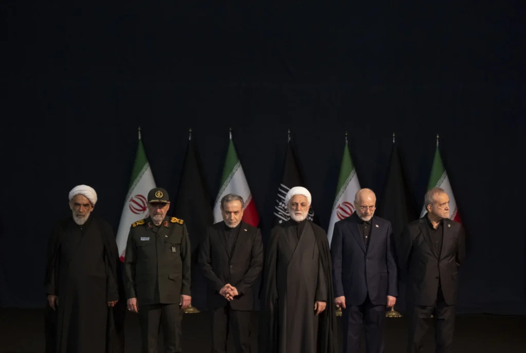 صمود النظام الإيراني يتحدى أقصى ضغوط ترامب A solemn group photograph of Iran's top civilian and military leadership standing in a unified line against a dark backdrop of Iranian and black mourning flags, attending a high-level state funeral, visually portraying the enduring and unified Iranian Regime Resilience that continues to defy external maximum pressure campaigns.