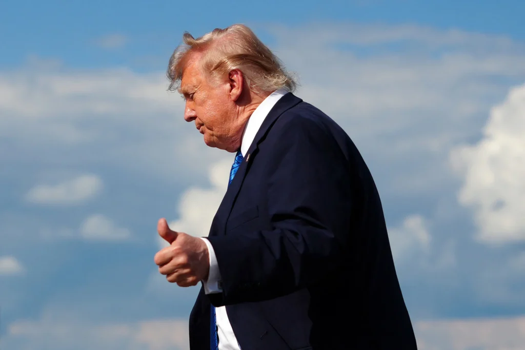 U.S. President Donald Trump gives a thumbs-up gesture amidst ongoing Trump Iran Negotiations against a clear blue sky.