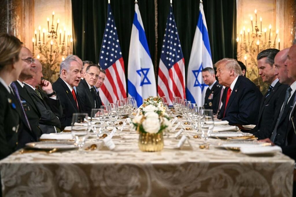 A formal diplomatic banquet featuring Israeli Prime Minister Benjamin Netanyahu and former US President Donald Trump seated across from each other at a long, elegantly decorated table, flanked by their respective delegations and military advisors, with alternating American and Israeli flags standing prominently in the background, visually illustrating the enduring strength of US-Israel ties and their joint defense partnership amidst global political shifts regarding military aid.