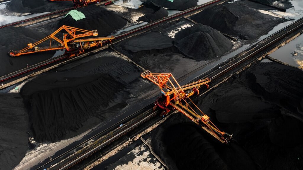 Energy transition shifts toward secure fuels worldwide An aerial view of large coal mounds and heavy industrial machinery at a storage facility in Ningbo, China, reflecting strategic energy security decisions within the global Energy transition.
