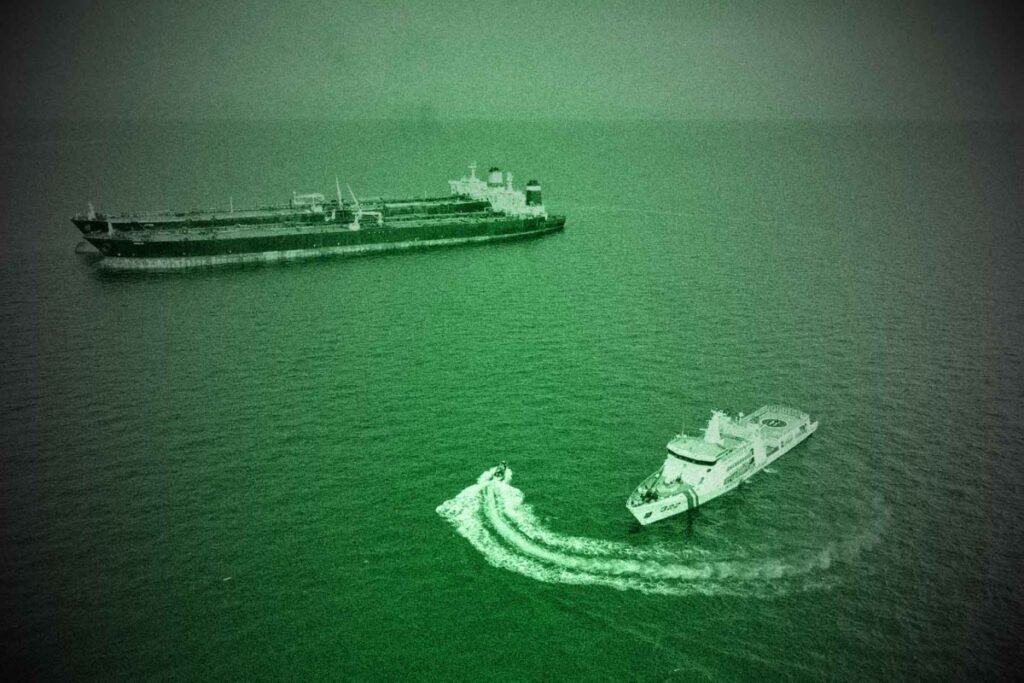 A green-tinted aerial view of a large oil tanker and a smaller vessel in open waters, illustrating the covert maritime tactics of the Iran Shadow Economy as it adapts to sanctions.