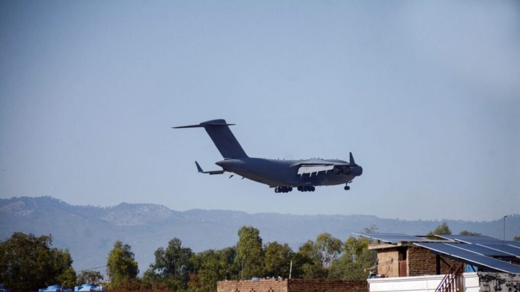 خطرات گسترش استراتژیک عمق پاکستان در خاورمیانه A Pakistani military transport plane flies over solar-paneled rooftops in Rawalpindi, highlighting the logistical reach of Pakistan strategic depth that risks overstretch in the Middle East.