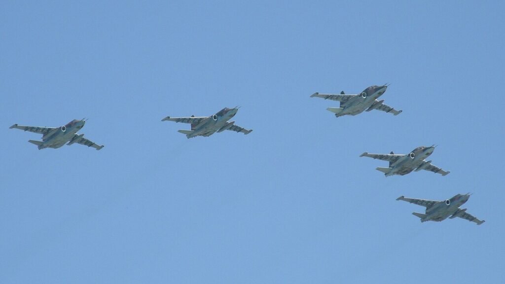 حرب الجو الإيرانية العراقية وضعت الطائرات الأمريكية في مواجهة الميغ السوفيتية Five Soviet-made Su-25 Frogfoot ground-attack jets fly in tight formation against a clear blue sky, their grey-green camouflage and distinctive twin-engine silhouettes visible as they bank together — the kind of Soviet aircraft that played a crucial role in the Iran-Iraq Air War, fighting Iran's advanced American jets to a standstill.