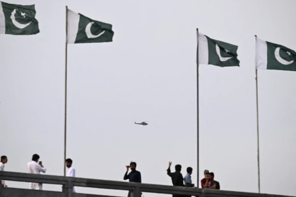 Military helicopter flying between Pakistani flags symbolizing Pakistan security guarantees.