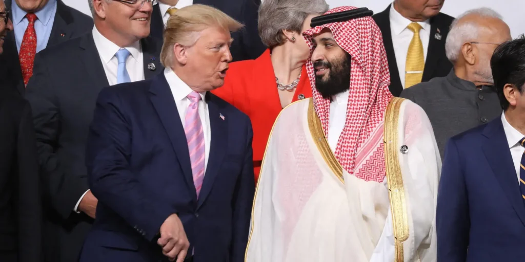 A formal photograph of President Donald Trump and Saudi Crown Prince Mohammed bin Salman sharing a friendly exchange at a crowded international summit, symbolizing the strategic US-Saudi alliance forged by the Saudi Nuke Agreement that critics argue prolongs the Iran war deadlock.