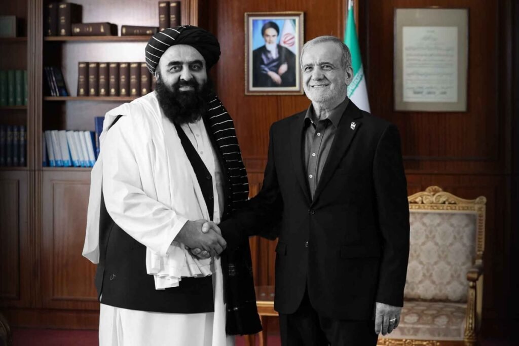 Iranian President Masoud Pezeshkian shaking hands with Afghanistan's Foreign Minister Amir Khan Muttaqi in Tehran, illustrating diplomatic ties shaping Iran-Afghanistan relations.