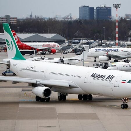 A Mahan Air passenger aircraft parked alongside a Turkish Airlines jet on an airport apron, reflecting aviation logistics and persistent sanctions compliance concerns rooted in the Halkbank Case.