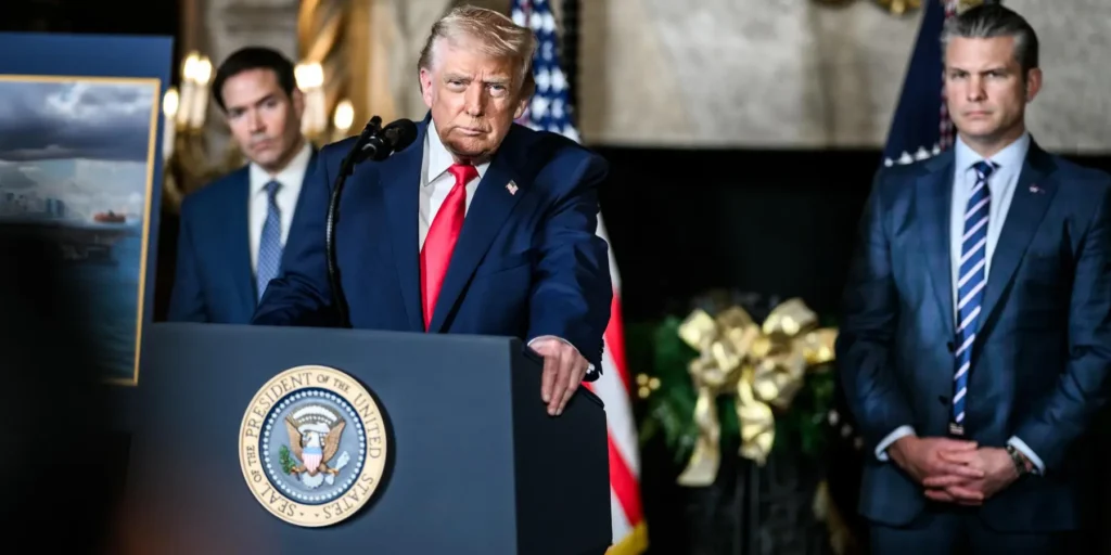 Donald Trump speaking at a presidential podium with Marco Rubio and Pete Hegseth in the background, highlighting political motives behind the Iran MOU.