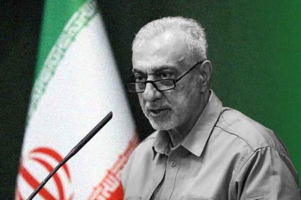 Iran's newly appointed Defence Minister Mehrdad Akhlaghi speaking in front of an Iranian flag, illustrating defense procurement and rebuilding efforts linked to Iran missile production.