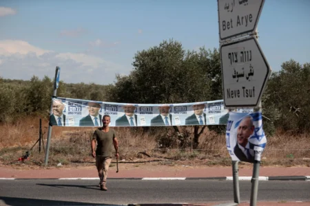 A man walks past roadside Likud campaign banners featuring Benjamin Netanyahu near Bet Arye amid the Knesset election.