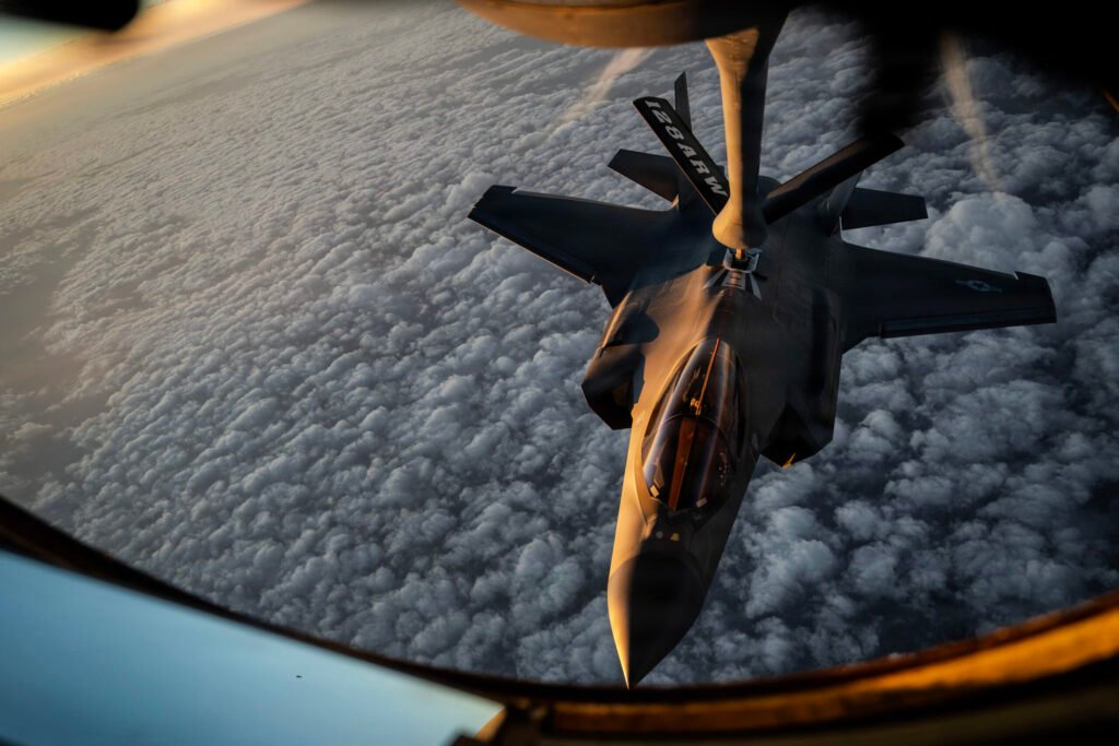 A US Air Force F-35A Lightning II fighter jet conducting aerial refueling from a KC-135 Stratotanker during military operations, illustrating risks behind an Escalation Against Iran.
