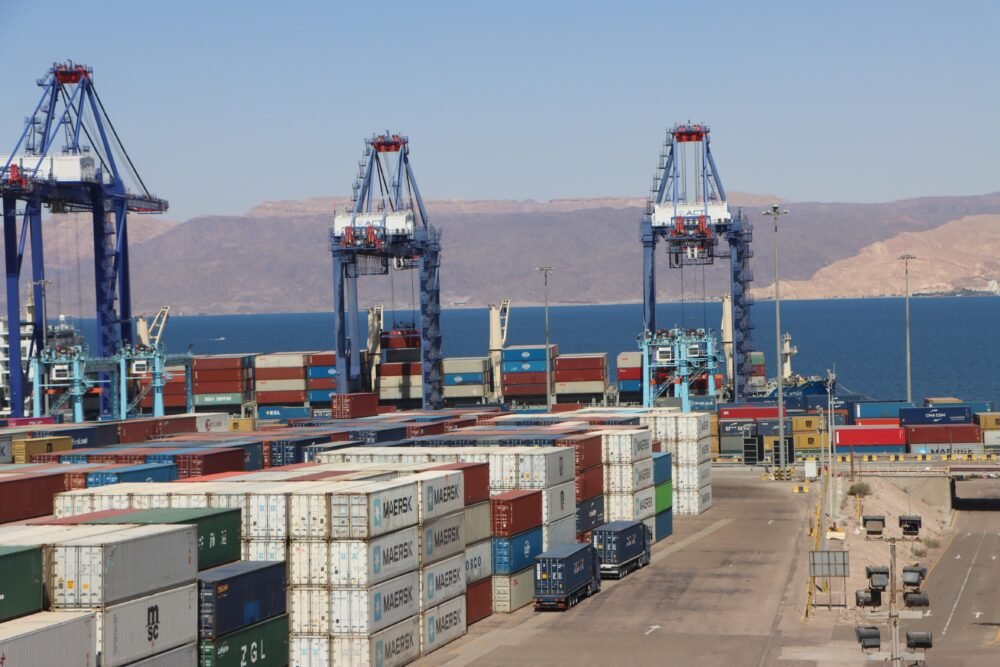 Jordan Economic Resilience Weathers Iran War Shocks Commercial shipping containers stacked at the Port of Aqaba with gantry cranes operating along the Red Sea coast, demonstrating Jordan Economic Resilience amid regional shocks.