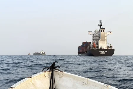 Commercial cargo and tanker ships navigating strategic maritime routes viewed from open water, highlighting security risks to Gulf Oil Exports through key chokepoints like Hormuz and Bab al-Mandab.