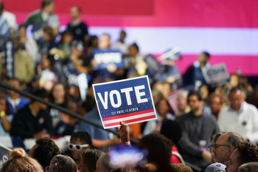 US Energy Policy Is Where the Midterms Will Hit Hardest A campaign rally attendee holding a blue Vote sign in Atlanta, Georgia, illustrating how voter turnout will directly impact the future of US Energy Policy in the midterm elections.