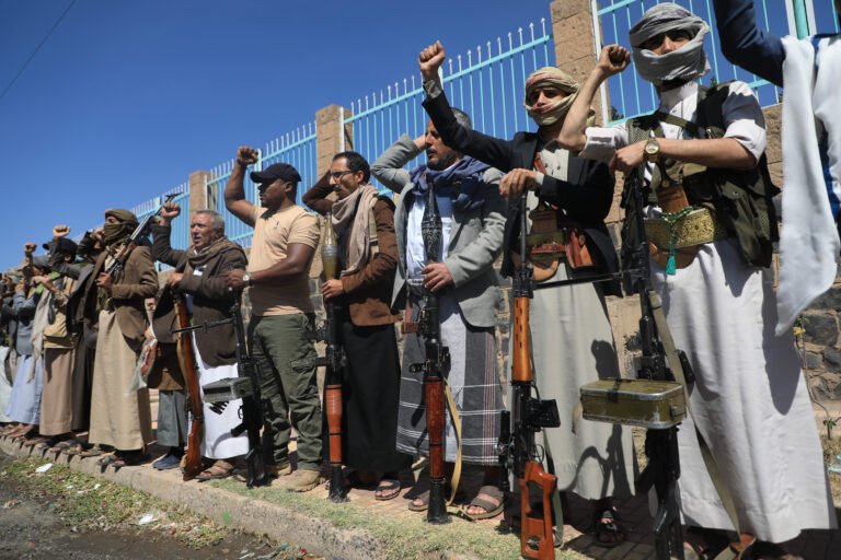 沙特-胡塞冲突实为围绕“愿景2030”的较量 Houthi supporters and armed fighters raising their fists and holding weapons during a tribal rally in Sanaa, Yemen, illustrating regional security threats tied to the Saudi Houthi Conflict.