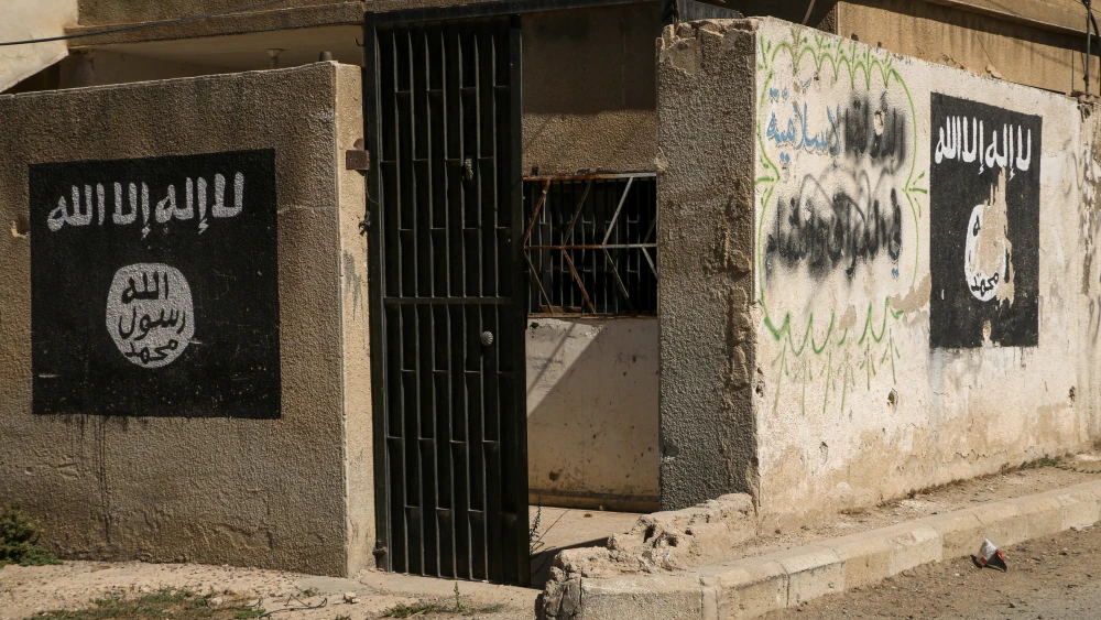 داراییهای تروریستی میتوانند پیروزی نظامی را به جنگی جدید تبدیل کنند ISIS flags and graffiti painted on the concrete wall of an urban compound, symbolizing hidden networks and terrorist assets that can spark insurgency following a military victory.