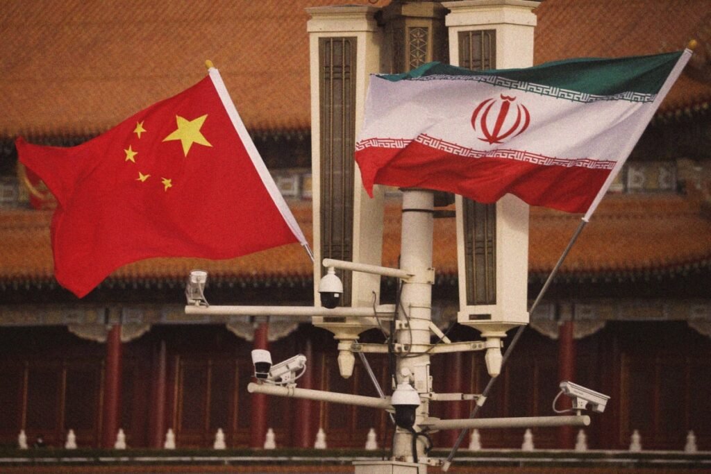 أزمة اليمن تضغط على بكين بين طهران والرياض Chinese and Iranian flags flying with surveillance cameras, illustrating Beijing's diplomatic dilemma in the Yemen Crisis between Tehran and Riyadh.