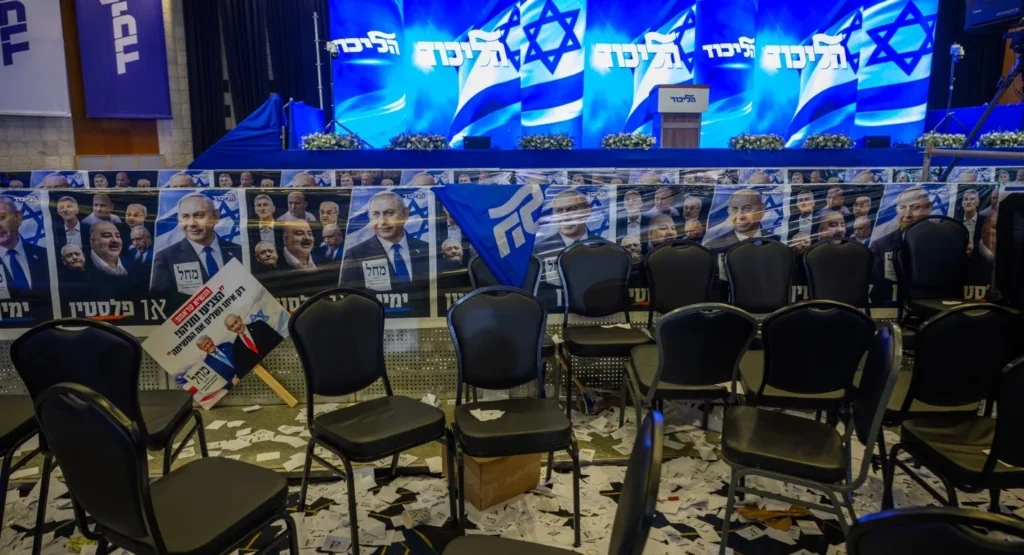 جمود الانتخابات الإسرائيلية يضع المنطقة في حالة استعداد للحرب Empty chairs and scattered papers at a Likud event with Netanyahu posters, illustrating the unresolved Israeli Election Deadlock.