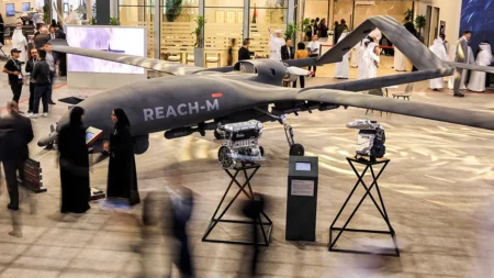 A large grey REACH-M drone displayed at a UAE defense exhibition with two engines on stands, highlighting the pursuit of UAE Defence Autonomy through engine ownership.