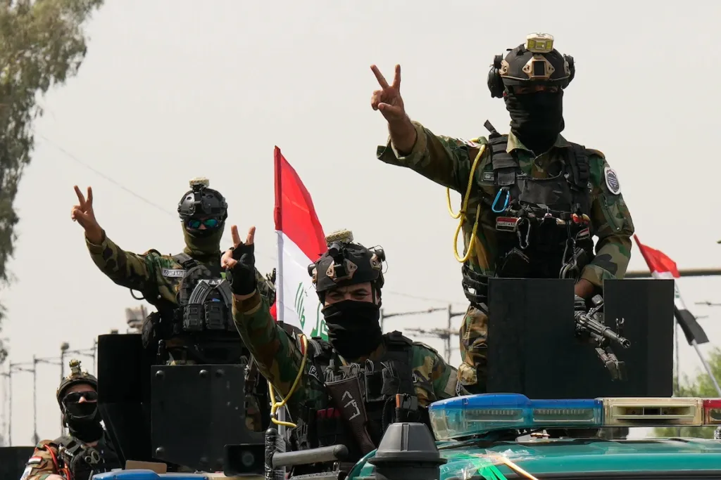 مجموعات المقاومة العراقية: انسحاب الولايات المتحدة هو احتواء، وليس تراجعاً Masked fighters of the Iraqi Resistance Groups in tactical gear raising victory signs atop a vehicle, illustrating why the US exit is perceived as no retreat.