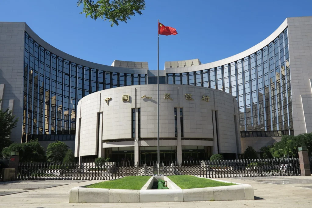 The headquarters building of the People’s Bank of China in Beijing under a clear blue sky, illustrating monetary policy constraints and economic challenges facing China’s Yuan Reserve Currency ambitions.
