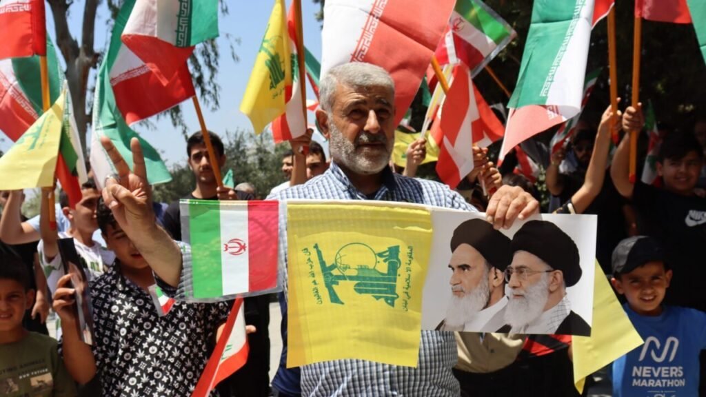Supporters holding Iranian and Hezbollah flags alongside portraits of Iranian leaders during a demonstration, symbolizing political pressure for Hezbollah Reconstruction.