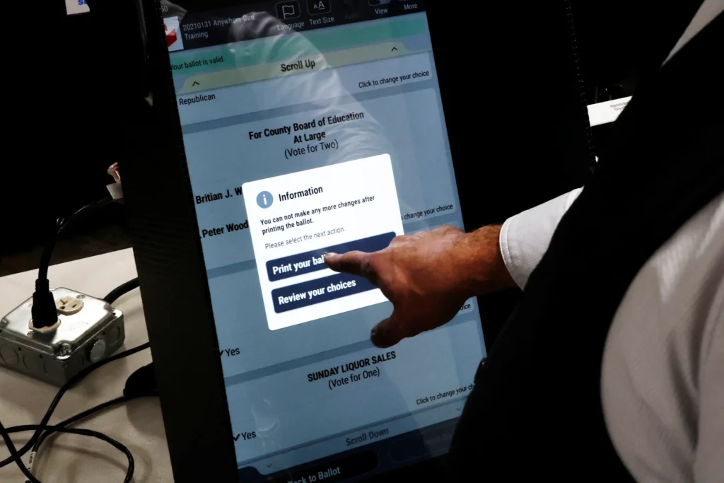 تأثير الانتخابات الأجنبية: الدفاعات التي dismantled ترامب A hand operating a digital voting machine touchscreen during election preparations, illustrating voting infrastructure and security vulnerabilities associated with Foreign Election Influence.