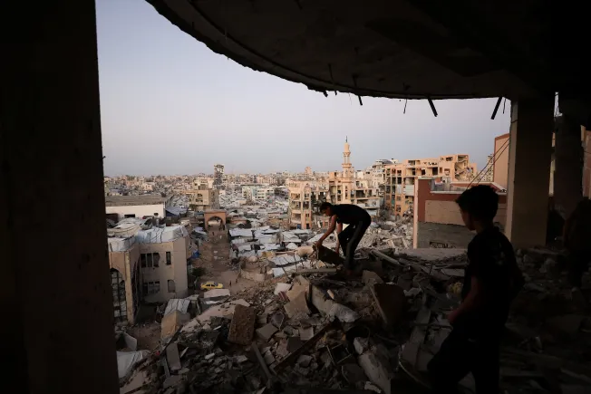 Gaza Ceasefire Collapse Is Israel’s Strategy, Not Failure Two boys stand on a pile of rubble overlooking a tent camp in Gaza City, capturing the widespread destruction and displacement following the Gaza ceasefire collapse.